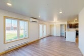 This single-story, 3-bedroom, 1-bathroom home offers a practical and comfortable layout designed for efficient everyday living. The open-concept living and kitchen area serves as the heart of the home, featuring light luxury vinyl plank flooring, recessed lighting, and a wall-mounted mini-split HVAC unit for year-round climate control. Large windows with warm wood trim flood the space with natural light and provide views of the surrounding outdoors, while French doors offer additional access and airflow. A baseboard heating system provides supplemental warmth throughout the main living area.

The kitchen is well-appointed with rich dark cabinetry, clean white countertops, a full suite of stainless steel appliances including a range, over-the-range microwave, and refrigerator, and durable LVP flooring. An open shelving unit provides additional pantry-style storage adjacent to the kitchen.

The three bedrooms are carpeted for comfort, each offering a quiet retreat. The primary bedroom benefits from a generous closet, and additional closet space is available throughout. The full bathroom features LVP flooring, a dark vanity with ample cabinetry, a soaking tub with accessibility grab bars, and direct access to a walk-in closet. A dedicated entryway with a windowed front door completes this functional and move-in-ready home.