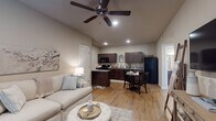 Located on Covington Way in Conway, Arkansas, this single-story residence offers a thoughtfully designed layout that balances functionality with a warm, neutral aesthetic throughout. The open-concept living and dining area serves as the heart of the unit, where warm-toned hardwood-style flooring flows seamlessly underfoot and a ceiling fan with integrated lighting overhead adds both comfort and visual interest. The living area provides ample space for relaxed seating and leads naturally into the dining space, which sits adjacent to the kitchen.

The kitchen is well-equipped with dark espresso cabinetry, light granite-style countertops, and black appliances including a range, over-the-range microwave, dishwasher, and full-size refrigerator. A galley-style section provides generous counter space for food preparation, while a peninsula or breakfast bar separates the kitchen from the dining area.

The bedroom is a calm, carpeted retreat featuring a ceiling fan, natural light from a window with curtains, and easy access to the bathroom. The bathroom continues the warm hardwood-style flooring, dark wood vanity with granite-topped counters, and a full tub-shower combination.

A stacked washer and dryer unit is tucked neatly behind a closet door, offering convenient in-unit laundry. The overall palette of beige, taupe, and dark wood tones creates a cohesive and inviting atmosphere throughout.