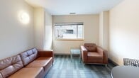 Located at 115 S Quarry St in Ithaca, NY, this one-bedroom, one-bathroom unit offers a smartly designed, single-floor layout that makes excellent use of its compact footprint. The living room serves as the heart of the unit, featuring plush carpet tiles in a neutral pattern, warm wall sconce lighting, and a window overlooking the surrounding neighborhood, providing a comfortable and inviting atmosphere. The bedroom is a quiet, well-proportioned retreat with carpeted flooring, clean white walls, and a window that brings in natural light. A standout feature of the unit is the built-in study nook, complete with a wide wood-surfaced desk, overhead open shelving, and additional lower storage — ideal for work or study. The bathroom is finished with large-format stone-look tile flooring, a full bathtub with shower, vanity with storage, and clean white walls that create a bright, functional space. A dedicated closet and hallway entry complete the layout. The unit's overall design is clean and modern, with a consistent neutral palette, carpeted living and sleeping areas, and practical built-in features throughout.