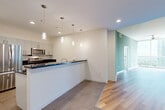 Located in the heart of downtown Orlando, this modern 2-bedroom, 2-bathroom residence offers a thoughtfully designed open-concept layout. The combined living, dining, and kitchen area forms the centerpiece of the home, highlighted by a sleek kitchen featuring stainless steel appliances, gray cabinetry, a tile backsplash, dark countertops, and a peninsula with pendant lighting overhead. Tile flooring anchors the kitchen and dining space, while warm hardwood flooring flows through the living area and into the primary bedroom. The spacious primary bedroom is bathed in natural light from dramatic floor-to-ceiling windows that frame sweeping panoramic views of the Orlando skyline, complemented by soft carpet and a ceiling fan. The second bedroom offers plush carpeting and ample natural light. Both bathrooms are finished with dark countertops, gray cabinetry, and clean tile work, including a glass-enclosed walk-in shower. The residence also includes three closets, a dedicated pantry, in-unit laundry, a utility room, and a private balcony. Sage green accent walls throughout add a touch of warmth and character to the contemporary aesthetic.