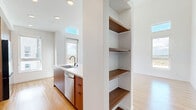 Located in San Diego, CA, this thoughtfully designed 3-bedroom, 2-bathroom single-floor residence offers a clean, contemporary aesthetic with high-end finishes throughout. The open-concept kitchen and living area serves as the heart of the home, showcasing a large center island with a white quartz countertop, warm walnut-toned cabinetry, white upper cabinets, a herringbone tile backsplash, and stainless steel appliances. Built-in open shelving adds both function and style to the layout. Soaring ceilings with expansive windows and clerestory glazing flood the living spaces with natural light, while direct balcony access frames sweeping outdoor views of the surrounding landscape. Warm-toned hardwood flooring runs seamlessly throughout, complementing the bright, white walls and recessed lighting. The primary bedroom is generously proportioned, benefiting from corner windows and balcony access that enhance the sense of openness. Additional bedrooms are well-sized with large windows capturing scenic views. The bathrooms are finished with quartz vanities, walnut cabinetry, and clean white tiling. A dedicated laundry room with a stacked Whirlpool washer and dryer adds everyday convenience. Six closets provide abundant storage across the home. A light-filled hallway connects all rooms, completing this modern and functional residence.