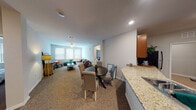 This single-story residence offers a thoughtfully designed open-concept layout that seamlessly connects the kitchen, dining, and living areas. The kitchen is a functional centerpiece, featuring rich warm-toned cabinetry, granite countertops, stainless steel appliances including a refrigerator, electric range, microwave, and dishwasher, and light wood-look tile flooring. A curved peninsula with an undermount sink provides additional workspace and naturally defines the transition into the dining and living spaces.

The living room is generously proportioned, highlighted by multiple windows dressed with vertical blinds that allow ample natural light. A ceiling fan overhead and a media console with a built-in electric fireplace add both comfort and character. Plush carpet extends throughout the living area and into each bedroom, contributing to a warm ambiance.

The bedrooms are well-sized, each featuring ceiling fans, carpeted floors, and windows with vertical blinds. Two full bathrooms serve the unit, both finished with granite-topped vanities and warm wood cabinetry. One bathroom includes a full soaking tub with a tiled surround, while the second features a clean, efficient layout. An in-unit laundry area completes the practical amenities of this well-rounded residence.