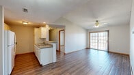 Located at 1454 W Lark St in Springfield, Missouri, this well-appointed single-story, 2-bedroom, 2-bathroom home offers a comfortable and functional layout. The open-concept kitchen and living area serves as the heart of the home, featuring vaulted ceilings, a ceiling fan, and rich hardwood-style flooring throughout. The kitchen is equipped with white cabinetry, a double stainless steel sink, a peninsula with a breakfast bar, and white appliances including a refrigerator, range, and built-in microwave. The living room is bright and inviting, with sliding glass patio doors that welcome natural light and provide outdoor access. A connecting hallway with textured ceilings and warm wood-trimmed doorways links the common areas to the private quarters. The generously sized primary bedroom features a tray ceiling, ceiling fan, plush carpeting, a built-in desk nook, and a private en-suite bathroom. The second bedroom also offers carpet, a ceiling fan, a window for natural light, and a walk-in closet. Both bathrooms are finished with hardwood-style flooring and include a tub-shower combination. Two dedicated closets provide ample storage throughout the home.