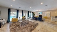 Located at 734 S Mesa Hills Dr in El Paso, TX, this single-floor space offers a well-appointed, open-concept layout designed for comfort and entertaining. The main lounge area is expansive and bright, featuring large windows dressed in teal drapes that frame views of an outdoor pool area, allowing generous natural light to fill the room. Large-format tile flooring runs throughout, complemented by plush area rugs that define distinct seating zones. A standout stacked-stone accent wall serves as the focal point of one lounge area, housing a sleek electric fireplace and wall-mounted TV, flanked by vibrant yellow accent chairs and a crystal chandelier overhead. The adjacent open seating zone provides additional flexible gathering space with a glass dining table and modern acrylic chairs. A dedicated wet bar area is a highlight of the space, featuring an extended granite countertop with bar seating, white subway tile backsplash, open wood shelving, pendant cage lighting, and a beverage refrigerator — ideal for hosting. The entry foyer is airy and welcoming, with French doors offering a bright, open feel. Throughout, the design blends contemporary furnishings with warm, inviting accents, creating a polished and functional environment.