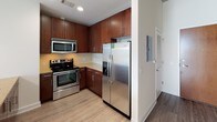 Located in the heart of uptown Charlotte, this single-floor residence blends industrial design with contemporary finishes. The open living area features light hardwood-style flooring and a dramatic exposed concrete ceiling supported by concrete columns, lending the space a bold, loft-inspired character. Floor-to-ceiling windows flood the living area with natural light while framing sweeping views of the Charlotte city skyline, creating a striking connection to the urban landscape outside.

The kitchen is well-appointed with rich dark wood cabinetry extending to the ceiling for ample storage, a full suite of stainless steel appliances including a side-by-side refrigerator, electric range, and over-the-range microwave, complemented by a tile backsplash and light countertops. A peninsula with pendant lighting provides both workspace and a casual dining option, opening seamlessly to the living area.

The bathroom offers a clean, neutral aesthetic with large-format tile on both the floors and tub surround. A soaking tub with an overhead shower, a built-in niche, and recessed lighting contribute to a functional and relaxing environment. Additional conveniences include an in-unit stacked washer and dryer. This residence delivers a compelling combination of architectural detail, modern amenities, and a prime urban location.