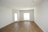 This single-floor residence is designed with an open-concept layout that seamlessly connects the kitchen and living areas. The main living space features warm-toned hardwood-style flooring and crisp white walls, creating a bright and airy atmosphere. Track lighting runs along the ceiling, providing functional illumination, while a large window with blinds allows natural light to filter in.

The kitchen is a standout feature, centered around a curved island with a quartz-style countertop, an undermount double sink, and pendant lighting overhead. White cabinetry lines the walls alongside stainless steel appliances, including a refrigerator, microwave, and electric range. The kitchen flows directly into the open living area, making the space ideal for entertaining.

The bedrooms are carpeted and well-proportioned, each equipped with ceiling fans and windows with blinds that provide natural light. The primary bedroom connects to a full bathroom featuring a double-sink vanity with grey countertops, ample cabinetry, and an adjacent walk-in closet with wire shelving. A compact half bathroom with a pedestal sink and hardwood-style flooring serves as an additional convenience. The overall design is clean, modern, and highly functional.