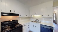 Located at 1515 S Mebane St in Burlington, North Carolina, this single-floor unit offers a practical and well-appointed layout with consistent finishes throughout. The kitchen is efficiently designed with ample white cabinetry, light countertops, a double-basin stainless steel sink with a black faucet, a black electric range with overhead exhaust, a dishwasher, and tile backsplash — all set atop durable wood-look flooring that extends into the main living areas. The living and dining areas feature the same warm-toned hardwood-style flooring, neutral walls with chair rail detailing, and windows that bring in natural light. Bedrooms are finished with plush carpeting and ceiling fans, creating a comfortable and quiet retreat. Each bedroom includes a window with blinds, allowing for natural light and ventilation. The bathroom is equipped with a tub-shower combination, toilet, and a vanity with a light countertop, complemented by wood-look flooring and textured walls. Throughout the unit, textured ceilings, clean white trim, and a neutral color palette provide a cohesive and move-in-ready aesthetic. The overall layout, as seen from the dollhouse view, is compact yet functional, with clear separation between living, kitchen, and sleeping areas.