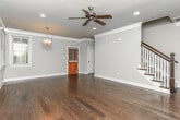 Located at 650 DeKalb St in Auburn, Alabama, this two-story home offers a well-appointed layout with a blend of classic finishes and functional design across both levels. The main floor welcomes you through a warm wood entry door into a spacious living area showcasing rich, dark hardwood flooring, crown molding, recessed lighting, and a ceiling fan — all bathed in natural light from windows fitted with white wood blinds. The kitchen is equipped with dark granite countertops, warm wood cabinetry with a beadboard panel detail, a stainless steel double-basin sink, and a stainless steel dishwasher, offering both style and practicality. A convenient half bathroom on this level features tile flooring, a wood vanity, and a window overlooking the greenery outside. Upstairs, the carpeted bedrooms provide a comfortable retreat, each with ceiling fans and natural light from well-placed windows. One bedroom features vaulted ceilings that add architectural character. The primary bedroom includes direct access to a private en-suite bathroom. Multiple full bathrooms throughout the home are finished with tile flooring, wood vanities, and tub-shower combinations with oil-rubbed bronze fixtures. Warm neutral tones flow consistently throughout, creating a cohesive and inviting atmosphere.