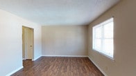 This two-story home offers three bedrooms and one and a half bathrooms, providing a well-rounded layout suitable for a variety of living arrangements. The interior features warm wood-look hard flooring that runs throughout the main living areas, adding both durability and a welcoming aesthetic. Neutral beige walls create a clean, versatile backdrop that complements a range of décor styles. The living area is generously proportioned, bathed in natural light from a large window fitted with horizontal blinds, offering both brightness and privacy. The textured popcorn ceiling adds a classic touch to the space. White baseboards provide a crisp contrast against the flooring, contributing to the overall tidy and well-maintained appearance of the home. The two-floor layout allows for a natural separation between living and sleeping areas, enhancing functionality and privacy. With its straightforward design, neutral palette, and practical finishes, this home presents a solid foundation for comfortable everyday living.