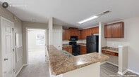 This one-bedroom, one-bathroom residence in Fayetteville, NC offers a well-organized single-floor layout designed for comfortable everyday living. The kitchen is a functional centerpiece, featuring warm medium-toned cabinetry, granite-style countertops, black appliances including a refrigerator, electric range, and built-in microwave, and a peninsula that opens toward the main living area. A convenient built-in desk nook with overhead cabinetry adds practical workspace. Light wood-style flooring runs throughout the kitchen and entry areas, while neutral carpet carries through the living spaces.

The living room is bright and welcoming, highlighted by a ceiling fan, soft natural light, and sliding glass doors that lead to a private balcony — offering outdoor views and ventilation. The bedroom is a comfortable retreat with plush carpeting, a ceiling fan, a natural light-filled window, and two closets for generous storage. Direct access to the bathroom is available from the bedroom.

The bathroom includes warm wood-toned vanity cabinetry, a light countertop with an integrated sink, wood-style flooring, and in-unit washer hookups, adding functional convenience. Neutral wall tones and clean finishes throughout create a cohesive, move-in-ready atmosphere.