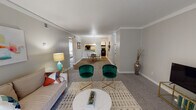 This single-floor residence offers a thoughtfully arranged layout that balances open communal spaces with comfortable private quarters. The living room is a welcoming focal point, featuring plush carpet flooring, crown molding, a textured ceiling, and a sliding glass door that fills the room with natural light. The space flows seamlessly into the dining area, which is defined by wood-look flooring, a pendant light overhead, and a pass-through window connecting directly to the kitchen — a practical detail that enhances the sense of openness. The kitchen is efficiently laid out in a galley style, equipped with white cabinetry, grey laminate countertops, a stainless steel sink, and black appliances including a refrigerator and dishwasher. Two bedrooms provide restful retreats, each with carpet flooring and neutral wall tones. The primary bedroom features dual sliding-door closets offering generous storage, while the secondary bedroom is well-sized and similarly appointed. A full bathroom serves the residence, complete with a white vanity, ample mirror space, and a shower with a curtain enclosure. Throughout the home, consistent neutral tones and crown molding details contribute to a clean, cohesive aesthetic.