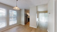 This single-floor residence offers a thoughtfully designed layout with consistent wood-look flooring running throughout the living spaces, bedrooms, and kitchen, creating a cohesive and easy-to-maintain interior. The living room is bright and open, highlighted by a ceiling fan with light fixture and a large sliding glass door fitted with vertical blinds that open to an outdoor view, filling the space with natural light. Adjacent to the living room, the dining area features a stylish pendant light and windows with horizontal blinds, offering additional illumination and a pleasant atmosphere for everyday dining. The kitchen is efficiently arranged with white cabinetry, light speckled countertops, a double stainless steel sink, and stainless steel appliances including a refrigerator, range, and dishwasher. A window above the sink adds natural light to the workspace. The bedrooms are comfortably sized, each with neutral walls, wood-look flooring, and windows with blinds that allow for privacy and light control. The bathroom features a tub-shower combination with white tile surround, light cabinetry with brushed nickel hardware, and light countertops. Textured ceilings are present throughout the residence, adding a classic finishing detail to every room.