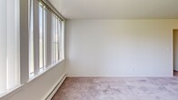 Located at 370 W Hopkins Ave in Pontiac, Michigan, this single-floor, two-bedroom, one-bathroom residence offers a practical and well-organized layout. The living room is a standout space, featuring large windows with vertical blinds that invite an abundance of natural light, neutral carpeting, and baseboard heating — creating a bright, comfortable environment. The galley-style kitchen is efficiently designed with warm wood cabinetry on both sides, dark laminate countertops, a stainless steel sink, tile flooring, and white appliances including a refrigerator and range, with direct sightlines into the living area. Both bedrooms are carpeted and finished with clean white walls. The primary bedroom features a double-door closet and its own ceiling light fixture, while the second bedroom similarly includes a spacious closet and a window for natural light. A connecting hallway ties the rooms together, providing a functional flow throughout the unit. The bathroom is clean and classic, featuring a full-size tub and shower combination with white tile surround. Throughout the space, the neutral color palette, consistent carpeting, and ample natural light contribute to a cohesive and move-in-ready atmosphere.