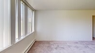 Located at 370 W Hopkins Ave in Pontiac, Michigan, this single-floor, two-bedroom, one-bathroom residence offers a practical and well-organized layout. The living room is a standout space, featuring large windows with vertical blinds that invite an abundance of natural light, neutral carpeting, and baseboard heating — creating a bright, comfortable environment. The galley-style kitchen is efficiently designed with warm wood cabinetry on both sides, dark laminate countertops, a stainless steel sink, tile flooring, and white appliances including a refrigerator and range, with direct sightlines into the living area. Both bedrooms are carpeted and finished with clean white walls. The primary bedroom features a double-door closet and its own ceiling light fixture, while the second bedroom similarly includes a spacious closet and a window for natural light. A connecting hallway ties the rooms together, providing a functional flow throughout the unit. The bathroom is clean and classic, featuring a full-size tub and shower combination with white tile surround. Throughout the space, the neutral color palette, consistent carpeting, and ample natural light contribute to a cohesive and move-in-ready atmosphere.