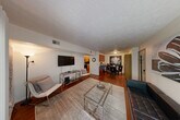 This well-appointed two-bedroom, two-bathroom residence in Howell, Michigan offers a thoughtfully designed single-floor layout. The living room is a welcoming centerpiece, featuring rich hardwood flooring, a textured ceiling, and a wall of sliding glass doors that flood the space with natural light and open onto a private balcony with outdoor seating. The open-concept flow connects the living area seamlessly to the dining room, making the space feel expansive and ideal for entertaining.

The galley-style kitchen is efficiently designed with warm wood cabinetry, granite countertops, a stainless steel sink, and black appliances including a range, refrigerator, and dishwasher. Both bedrooms are comfortably sized and carpeted, offering a quiet retreat. The spacious primary bedroom benefits from a large window with greenery views, while both rooms include dedicated closet storage. Three closets total provide ample storage throughout.

The two bathrooms are clean and functional — one features a walk-in glass-door shower, while the other includes a full tub-shower combo with tile flooring and a granite-topped vanity. A dedicated laundry area adds everyday convenience. The residence is rounded out by a hallway that connects all spaces efficiently, contributing to the home's practical and comfortable overall flow.