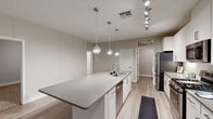 Located along North Scottsdale Road in Scottsdale, Arizona, this well-appointed one-bedroom, one-bathroom residence offers a thoughtfully designed single-level layout with an open, airy feel. The combined kitchen and living area serves as the heart of the home, showcasing a large central island with quartz countertops, an undermount sink, and stylish globe pendant lighting. White shaker cabinetry with glass-front upper accents, a full suite of stainless steel appliances, and a track lighting system complete the kitchen's modern aesthetic. Light wood-look flooring flows throughout the main living areas, enhancing the bright, neutral color palette. The living area features a ceiling fan and direct access to a private patio through sliding glass doors, flooding the space with natural light and outdoor views. The carpeted bedroom is a comfortable retreat with its own ceiling fan, a window with outdoor views, and access to multiple closets, including a generously sized walk-in with built-in shelving and hanging rods. The clean, white bathroom offers a full soaking tub and shower combo. A dedicated laundry room with full-size washer and dryer adds everyday convenience. Three closets throughout the residence provide ample storage for comfortable living.