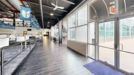 This impressive 4,530 square foot facility in Biloxi, MS, showcases a blend of modern architecture and industrial design. The space is characterized by its open floor plan, high ceilings, and abundant natural light streaming through large windows and skylights. The interior features sleek gray wood flooring throughout, creating a cohesive look across different areas.

A striking black metal staircase with horizontal railings serves as a focal point, leading to a mezzanine level that overlooks the main floor. The exposed ceiling reveals structural elements painted in contrasting colors, adding visual interest and emphasizing the building's height.

The facility includes various functional areas, such as a fitness center with state-of-the-art equipment, and a stunning indoor swimming pool visible through large glass panels. Multiple seating areas with contemporary furniture are scattered throughout, providing comfortable spaces for relaxation or casual meetings.

Glass partitions and walls create separate yet connected spaces, maintaining an open feel while allowing for privacy when needed. The use of white walls and ample lighting contributes to the bright, airy atmosphere. Motivational signage and modern artwork add pops of color and personality to the space.

This versatile venue appears well-suited for a range of activities, from fitness classes and swimming to corporate events and social gatherings, making it a dynamic addition to the community.
