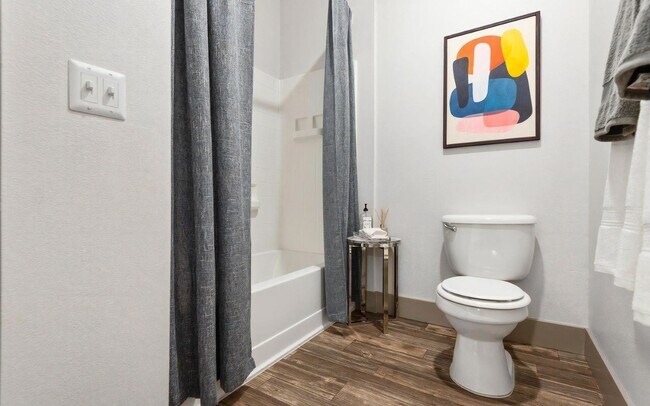 Baño compacto con inodoro, bañera y una pequeña mesa auxiliar - REVERB
