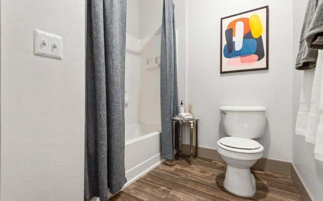 Compact Bathroom Featuring Toilet, Tub, and Small Accent Table - REVERB