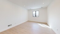 Located at 1060 Main St in Millis, MA, this thoughtfully designed two-bedroom, two-bathroom residence offers a clean, modern aesthetic across a single well-organized floor. The open-concept living area seamlessly connects the kitchen, dining, and living spaces, creating a bright and airy atmosphere flooded with natural light. The kitchen is a standout feature, showcasing crisp white shaker cabinetry, open wood shelving, a large center island with a warm wood base and white quartz countertop, stainless steel appliances, and stylish globe pendant lighting. Light-toned hardwood flooring flows consistently throughout the home, enhancing the sense of openness. Both bedrooms are generously sized and benefit from natural light through black-framed windows that frame outdoor views of the surrounding landscape. Each bedroom is equipped with a ceiling fan and recessed lighting. The bathrooms are finished with quality materials, including tile flooring, warm wood vanities, illuminated mirrors, and a tiled tub and shower combination. Storage is plentiful, with five closets including a spacious walk-in featuring built-in wire shelving. A dedicated laundry area adds everyday convenience, completing this well-appointed and move-in-ready home.