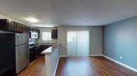 Located at 1700–1712 Taft Ave in the heart of Hollywood, Los Angeles, this single-floor unit offers a well-designed, open-concept layout finished with rich hardwood flooring that extends throughout the space. The interior is painted in a soft, neutral gray palette, lending a clean and cohesive aesthetic across all rooms.

The kitchen is a functional highlight, featuring dark espresso cabinetry that reaches toward the ceiling, granite-style countertops, and a full suite of stainless steel appliances including a refrigerator, range, microwave, and dishwasher. A peninsula counter separates the kitchen from the main living area, creating a natural boundary while maintaining the open feel of the space. A window above the sink provides natural light directly into the kitchen.

The living area is generously proportioned, with sliding glass doors fitted with vertical blinds that allow for both light control and access to the exterior. The spacious, open layout offers flexible arrangement options for furnishings.

The bedroom is a well-sized, quiet room with a window, hardwood floors, and a standard entry door. The bathroom features white subway tile surrounding the tub and shower, chrome fixtures, and a clean, minimalist design. Overall, the unit presents a practical yet polished living environment in a prime Los Angeles location.