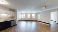 Located at 20 Day St in Norwalk, Connecticut, this single-floor unit offers a well-designed, open-concept layout finished with rich hardwood-style flooring throughout the main living areas. The expansive living room is bathed in natural light from multiple large windows, creating a bright and welcoming atmosphere with clean neutral walls and track lighting accents.

The kitchen is thoughtfully appointed with a two-tone cabinetry scheme — crisp white upper cabinets paired with dark espresso lower cabinets — complemented by light countertops and a full suite of stainless steel appliances, including a refrigerator, electric range, microwave, and dishwasher. An in-unit washer and dryer area is also present, adding everyday convenience.

The bedrooms are generously sized, each featuring hardwood-style floors, neutral walls, and ample natural light from large windows. One bedroom includes a walk-in closet with built-in shelving for organized storage.

Two bathrooms serve the unit, each finished with tile flooring, white vanity cabinetry, and clean fixtures. One bathroom features a full tub-and-shower combination, while the second offers a vanity and toilet in a functional layout. The overall design emphasizes a clean, modern aesthetic with practical finishes throughout.
