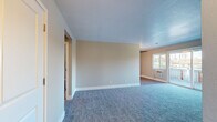 This one-bedroom, one-bathroom unit in Walnut Creek, California offers a thoughtfully organized single-level layout. The living room is the largest area of the home, featuring plush blue-gray carpeting, neutral beige walls, and abundant natural light streaming through a large window and sliding glass door that opens to an outdoor space, providing pleasant views of the surrounding neighborhood. A wall-mounted air conditioning unit serves the living area.

The kitchen is efficiently designed with light wood-look vinyl flooring, white shaker-style cabinetry, dark quartz countertops, and a full suite of stainless steel appliances including an electric range, over-the-range microwave, refrigerator, and dishwasher. A sink with updated hardware is positioned beneath upper cabinets.

The bedroom offers comfortable carpeting, a large window with natural light and baseboard heating, and a mirrored sliding-door closet providing ample storage. A hallway connects the rooms and leads to the entrance.

The bathroom includes wood-look vinyl flooring, a white vanity with dark countertop, a large mirror, and a full tub-shower combination with tile surround and a privacy window.