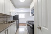 Located at 246 King St E in Clarington, Ontario, this one-bedroom, one-bathroom unit offers a well-organized layout across a single floor. Polished parquet hardwood flooring flows throughout the living areas and bedroom, lending a warm and classic character to the space.

The open-concept living and dining area is bright and airy, benefiting from natural light that pours through large sliding glass doors leading to a private balcony — an ideal spot for enjoying outdoor views. Baseboard heating runs along the perimeter, ensuring year-round comfort.

The kitchen is efficiently designed in a galley style, featuring white cabinetry with modern hardware, a tile backsplash, and stainless steel appliances including a refrigerator, stove, built-in microwave, and dishwasher. Light tile flooring in the kitchen offers a clean contrast to the warm parquet throughout the rest of the unit.

The bedroom is a comfortable size, complete with a double-door closet and a window that allows natural light and outdoor views. The bathroom is neatly finished with light tile flooring, a tiled tub-and-shower surround in a neutral taupe tone, and clean white fixtures. The overall palette of the unit is crisp and neutral, creating a bright and move-in-ready atmosphere.