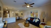 This thoughtfully designed 2-bedroom, 2-bathroom residence spans a single floor, offering a comfortable and functional layout ideal for everyday living. The open-concept living area serves as the heart of the home, featuring warm hardwood-style flooring, crown molding, and a ceiling fan with light fixture that adds both style and practicality. Large colorful wall art contributes to a vibrant and welcoming ambiance throughout the space. The living room provides ample space for relaxed seating arrangements, centered around a plush area rug and a sleek accent table. Adjacent to the living area, the dining space flows naturally from the kitchen, which is defined by pendant lighting and white cabinetry that lend a clean, modern aesthetic. The open sightlines between the kitchen, dining, and living areas create a cohesive and social environment. The layout maximizes the sense of space across the floor plan, ensuring each area feels connected yet purposeful. With two well-appointed bedrooms and two full bathrooms, this residence offers both privacy and convenience. The overall design balances contemporary finishes with a warm, inviting atmosphere, making it a comfortable and visually appealing place to call home.