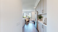 Located along the prestigious North Lincoln Park West corridor in Chicago's Lincoln Park neighborhood, this single-floor residence offers a thoughtfully designed open layout with high-end contemporary finishes throughout. Wide-plank hardwood-style flooring flows seamlessly from room to room, anchoring a bright, cohesive aesthetic defined by crisp white walls and recessed lighting.

The chef's kitchen serves as a centerpiece of the living area, featuring a large quartz waterfall island with bar seating, custom gray shaker cabinetry, a sleek stainless steel hood vent, black-framed multi-pane windows, and premium stainless steel appliances. An adjoining dining area and open living room benefit from abundant natural light and verdant treetop views.

The spacious primary bedroom is a serene retreat with multi-pane windows, ample closet storage, and a connected en-suite bathroom showcasing a glass-enclosed walk-in shower adorned with striking mosaic tile, a vessel sink, and clean white finishes. A secondary bathroom features a full soaking tub and shower combination with a white subway tile surround, undermount sink, and warm gold hardware accents. Additional bedrooms offer generous closet space with built-in shelving. The overall ambiance is modern, refined, and filled with natural light.