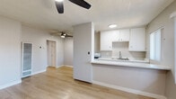 Located at 3351 Marine Ave in Gardena, California, this well-appointed one-bedroom, one-bathroom unit offers an efficient and comfortable single-floor layout. Light wood laminate flooring runs throughout, lending warmth and continuity to the entire space.

The combined living room and kitchen area forms the heart of the unit. The living room is bright and open, featuring neutral gray walls, a ceiling fan with integrated lighting, and vertical blinds that filter natural light through a front-facing window. A hallway connects the living area to the rest of the unit, keeping the floor plan organized and easy to navigate.

The kitchen is designed for practical use, featuring white cabinetry, a gas range, a single-basin sink, light countertops, and open shelving for additional storage. A window at the end of the kitchen allows natural light to brighten the space.

The bedroom is a comfortable retreat with its own ceiling fan, a window with views of greenery outside, and a full built-in closet system with sliding doors and upper cabinetry — providing generous storage capacity.

The bathroom includes a tub and shower combination with white tile surround, a window for natural ventilation, and a white vanity with under-sink storage. Clean finishes throughout maintain a cohesive, understated aesthetic across the entire unit.