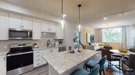 This well-designed single-floor residence offers a seamless blend of modern style and functional living. The open-concept kitchen is a standout, featuring crisp white shaker cabinetry, granite countertops, a subway tile backsplash, and stainless steel appliances including a French door refrigerator and range. A large center island with seating anchors the space, illuminated by elegant glass pendant lights. Wood-style flooring flows throughout the main living areas, connecting the kitchen to a bright, comfortable living and dining space that benefits from natural light through generously sized windows.

The primary bedroom is a serene retreat, complete with a ceiling fan, plush carpeting, and direct access to an en-suite bathroom. The primary bath features a dual-sink vanity with grey cabinetry, white quartz countertops, marble-look tile flooring, a backlit mirror, and a walk-in closet. A second bedroom offers its own closet and a calm, neutral aesthetic. The second full bathroom mirrors the same refined design language, with marble-look tile, a soaking tub with shower, and a single vanity with a backlit mirror. Throughout, black hardware accents provide a cohesive and contemporary finishing touch.