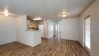 Located at 2601 Sarah Ave in McAllen, Texas, this single-floor unit offers a practical and comfortable layout designed for everyday living. Rich wood-look vinyl flooring runs consistently throughout the entire space, providing a cohesive and low-maintenance foundation.

The open-concept living and dining area flows naturally from the front entry, which is accessed through a windowed door that allows natural light to filter in. Adjacent to the living space, the kitchen is efficiently designed with light oak cabinetry offering ample storage, light-toned countertops, and white appliances including a gas range, refrigerator, and dishwasher. A peninsula-style breakfast bar separates the kitchen from the living area, creating an ideal spot for casual dining or meal prep.

A hallway connects the main living areas to the private quarters. The bedrooms are comfortably sized, each featuring ceiling fans for air circulation and neutral wall tones that lend a clean, move-in-ready feel. The bathroom is equipped with a full tub-shower combination, a wall-mounted vanity mirror with built-in shelving, and accessibility-friendly grab bars. The overall design is practical and straightforward, making this unit a functional and welcoming space in the heart of McAllen.
