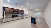 Located at 907 US-80 E in Pooler, Georgia, this single-floor unit offers a well-designed open-concept layout that seamlessly connects the kitchen and living areas. The kitchen is a standout feature, showcasing rich dark wood cabinetry — including a built-in wine rack — paired with granite countertops, a mosaic tile backsplash, and a full suite of black appliances including a range, over-the-range microwave, refrigerator, and dishwasher. A peninsula with seating potential provides both additional prep space and a natural divider from the living area. The spacious living room features light wood-style flooring and a ceiling fan, while large windows allow natural light to fill the space and offer views of the surrounding greenery. Bedrooms are carpeted for comfort and include windows with blinds. The bathrooms are finished with wood-style flooring and white fixtures; one features a walk-in shower, while another offers a shower-tub combo. Throughout the unit, clean white walls, recessed lighting, and consistent flooring choices create a cohesive and modern aesthetic well-suited for everyday living.