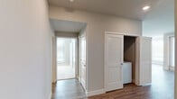 This single-story residence is designed with a clean, contemporary aesthetic and a practical layout. The kitchen serves as a central highlight, outfitted with rich dark wood cabinetry, stainless steel appliances including a gas range, microwave, dishwasher, and refrigerator, a subway tile backsplash, and track lighting overhead. A peninsula with a wood-paneled front and light stone countertop connects the kitchen to the open living area, which features warm wood-look hardwood flooring and pendant lighting.

The bedrooms are carpeted and filled with natural light from large windows fitted with blinds. The primary bedroom includes a ceiling fan and generous proportions. Both bathrooms share a consistent design language, featuring large-format marble-look tile flooring, a tub-shower combination with matching tile surround, a dark wood vanity with light countertops, and wall-mounted cabinetry. The primary bathroom also connects directly to a walk-in closet with built-in shelving.

A dedicated in-unit laundry closet with louvered doors is conveniently located in the hallway. Throughout the residence, neutral walls, white trim, and recessed lighting create a bright, cohesive, and move-in-ready atmosphere.