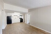 Located at 3237 Yanceyville St in Greensboro, NC, this single-floor unit offers a functional and well-organized layout with two bedrooms, two bathrooms, and a dedicated utility room. The open-concept kitchen and living area serves as the heart of the home, featuring warm wood-look flooring that extends throughout the unit. The kitchen is equipped with white shaker-style cabinetry, granite-look countertops, a stainless steel sink, and black appliances including a refrigerator, electric range, and under-cabinet range hood — all set against a textured ceiling with bright overhead lighting. The spacious living area flows naturally from the kitchen, providing a versatile and connected common space. Both bedrooms offer wood-look flooring, neutral wall tones, and windows that bring in natural light, with wall-mounted HVAC units for individual climate control. The primary bedroom is generously sized and includes closet access. The two bathrooms are cleanly finished, with one featuring a white vanity with granite-look countertops and a full tub/shower combo. With five closets distributed throughout, storage is plentiful. The hallway connects all rooms efficiently, completing this practical and neatly appointed single-level home.