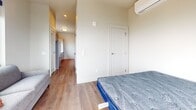 Located at 124 Langdon Street in Madison, Wisconsin, this 350-square-foot, one-bedroom, one-bathroom apartment delivers a thoughtfully designed modern living experience. The open layout maximizes every square foot, with warm hardwood-style flooring flowing throughout the entire unit. The primary bedroom, spanning 290 square feet, features a wall-mounted mini-split HVAC unit for individualized climate control and a floor-to-ceiling sliding glass door that opens to a private balcony showcasing sweeping views of the lake. A large picture window in the living area frames elevated city views of the Madison skyline, flooding the space with abundant natural light. The kitchen is efficiently appointed with stainless steel appliances, a double-basin sink, and ample cabinetry. A hallway connects the main living area to the bathroom, which features a full tub-shower combination, a gray vanity with white countertop, and hardwood-style flooring consistent with the rest of the unit. Clean white walls, recessed lighting, and contemporary door hardware contribute to the unit's crisp, modern aesthetic. The well-organized floor plan makes efficient use of space, offering both functionality and comfort in a prime Madison location.