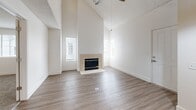 Located at 1710 NE Multnomah St in Portland, OR, this two-story residence offers three bedrooms and two bathrooms across two thoughtfully laid-out floors. The main level impresses with soaring vaulted ceilings in the living room, creating an airy, open atmosphere complemented by a tile-surround fireplace flanked by windows that invite natural light. Light-toned wood-style flooring runs throughout the main level, adding warmth and continuity. The kitchen features rich cherry wood cabinetry, granite countertops, a stainless steel range and refrigerator, and a dishwasher — all framed by a striking pendant light that descends from the dramatic ceiling height. The main level also includes carpeted bedroom space and a full bathroom with a tiled tub-shower combo. Upstairs, the second floor provides additional bedroom accommodations, including the generously sized primary bedroom, all finished with plush carpet and windows offering outside views. The upper level features angled architectural details reflecting the vaulted roofline below. A second full bathroom with a clean, white tiled tub-shower completes the upper floor. Clean white walls, consistent finishes, and a practical two-story layout make this residence a well-organized and comfortable Portland home.