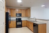Located at 4640 Daisy Reid Ave, Unit 306 in Woodbridge, Virginia, this one-bedroom, one-bathroom residence offers a thoughtfully organized single-level layout. The open-concept kitchen and living area serves as the heart of the home, where the kitchen is equipped with warm honey-toned cabinetry, black appliances including a refrigerator, range, microwave, and dishwasher, and granite-style countertops. A peninsula with bar seating and an integrated sink seamlessly connects the kitchen to the living area, making the space ideal for both cooking and entertaining. Light ceramic tile flooring runs throughout the kitchen, providing a clean, durable surface. The generously sized bedroom features plush wall-to-wall carpeting, crisp white walls, and multiple windows fitted with blinds that allow for ample natural light and outdoor views. A built-in window bench adds a functional architectural detail to the bedroom. A dedicated closet provides convenient storage. The bathroom includes a warm wood-toned vanity with countertop, tile flooring, and a clean, straightforward layout. Throughout the residence, neutral tones and consistent finishes create a cohesive and welcoming atmosphere.