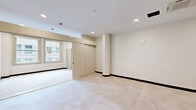 Located at 929 Walnut St, Unit 404 in the heart of Kansas City, MO, this thoughtfully designed single-floor unit offers a clean, modern aesthetic with a neutral color palette and light-toned tile flooring throughout. The open main living area is bright and versatile, featuring recessed lighting, a ceiling-mounted HVAC unit, and a structural column accent that adds an urban character to the space. Large windows allow natural light to filter in, enhancing the airy feel of the room.

The kitchen is efficiently laid out along a single wall and is well-appointed with two-tone cabinetry — warm natural wood lower cabinets paired with crisp white upper cabinets — all accented by sleek matte black hardware. Stainless steel appliances include a range with oven, built-in microwave, dishwasher, and refrigerator, complemented by a white quartz countertop and an undermount sink with a matte black faucet.

The full bathroom continues the modern design language with a warm wood vanity, white countertop, and matte black fixtures. A spacious walk-in shower features a frameless sliding glass door with black trim. Notably, a stacked washer and dryer unit is conveniently located adjacent to the bathroom, offering practical in-unit laundry.