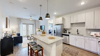 This single-floor residence offers a thoughtfully designed open-concept layout across two bedrooms and two bathrooms. The kitchen serves as a central hub of the living space, featuring white shaker-style cabinetry, granite countertops, a subway tile backsplash, and stainless steel appliances including a refrigerator and dishwasher. A large granite-topped island with pendant lighting and bar seating connects seamlessly to the living area, making it ideal for both everyday living and entertaining.

The living room is bright and welcoming, featuring wood-look flooring, a ceiling fan, and French doors that allow abundant natural light. The primary bedroom offers a comfortable, carpeted retreat with tall ceilings, access to a dedicated bathroom, and a walk-in closet equipped with wire shelving and hanging rods. Both bathrooms are finished with granite vanity countertops, undermount sinks, and light wood-toned cabinetry. A hallway connects the bedrooms to the main living areas, providing a practical flow throughout the unit. The clean white walls and consistent modern finishes create a cohesive, contemporary ambiance across the entire space.