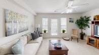 This single-floor residence at 5749 Colin Village Way in Winston-Salem, NC offers a well-designed layout with a comfortable blend of functionality and warmth throughout its living spaces. The living room serves as the heart of the home, featuring plush carpeting, a ceiling fan with light fixture, and multiple windows alongside a set of French doors that invite generous natural light and provide outdoor access. The neutral color palette creates a calm, welcoming ambiance throughout. Adjacent to the living area is a dedicated dining space, sized to accommodate a round table and chairs, accented by tasteful wall décor and carpeted flooring that transitions from the main living zone. The kitchen is efficiently laid out with warm wood cabinetry, granite-style countertops, and black appliances including a range, microwave, and refrigerator. Light tile flooring and a peninsula with a sink add practical workspace and flow. The bedroom is a serene retreat with soft carpet, multiple windows dressed in sheer curtains and blinds, and a ceiling fan overhead. The full bathroom features a wood-toned vanity with a large mirror, a shower-tub combination, and tile flooring, maintaining the clean and neutral aesthetic found throughout the residence.