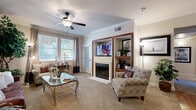 This thoughtfully designed single-floor residence offers a comfortable and stylish living experience across a well-utilized floor plan. The living room serves as the heart of the home, featuring plush carpeting, crown molding, a ceiling fan, and large windows that invite abundant natural light. A built-in entertainment center with wood-framed shelving flanks a classic fireplace, creating a warm and inviting focal point. An adjacent dining area with hardwood-style flooring transitions seamlessly from the living space, providing an intimate setting for meals. The galley-style kitchen is efficiently appointed with rich wood cabinetry, granite-style countertops, a double sink, and black appliances including a refrigerator, range, and microwave. The generously sized primary bedroom features plush carpeting, crown molding, a ceiling fan, and direct access to an outdoor patio through a glass door, allowing for views and fresh air. The full bathroom is well-finished with warm hardwood-style flooring, a tub-shower combination with a sliding glass door, a wood vanity with granite-style countertops, and a high window for natural light. A hallway with a dedicated nook provides additional functional space, completing this well-rounded and comfortable residence.
