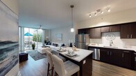 This well-appointed single-floor residence offers a thoughtfully designed open-concept layout that seamlessly connects the kitchen, dining, and living areas. The kitchen is a standout feature, showcasing rich dark cabinetry, a full suite of stainless steel appliances including a refrigerator, range, microwave, and dishwasher, and a generous island with a crisp white countertop that doubles as a casual dining space with seating. Track and pendant lighting illuminate the kitchen, adding both function and style. The living room is bright and inviting, highlighted by a large sliding glass door that opens to a private outdoor balcony, allowing abundant natural light and outdoor views to flow into the space. A ceiling fan adds comfort to this area. Wood-style flooring runs throughout the main living spaces, contributing to the home's modern, cohesive aesthetic. The two bedrooms are comfortably scaled, each featuring ceiling fans and windows that bring in natural light. The full bathroom is finished with dark cabinetry, a white countertop vanity, wood-style flooring, and a tiled tub-shower combination. Overall, the residence presents a clean, contemporary design with quality finishes throughout.