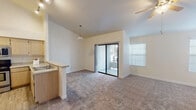 This single-floor residence offers a thoughtfully designed layout that balances comfort and functionality. The open-concept living area is a standout feature, boasting vaulted ceilings, plush wall-to-wall carpeting, and a ceiling fan overhead. A built-in fireplace with an arched decorative surround serves as the room's focal point, complemented by multiple windows with blinds that invite natural light. A sliding glass door opens directly to a private balcony, seamlessly connecting indoor and outdoor living. The kitchen is efficiently designed with light wood cabinetry, stainless steel appliances including a refrigerator and microwave, a black range, and a raised breakfast bar with stone-look countertops. Track lighting above and a pendant light near the bar area add a warm, functional glow. The bedrooms are generously proportioned, each featuring soft carpeting and distinctive arched windows that lend architectural character. One bedroom includes a sliding-door closet with a built-in rod for added storage. The bathroom is well-appointed with a tiled tub-shower combination accented by a decorative border, a wide vanity mirror, and a single-sink countertop. Throughout, the neutral color palette and clean finishes create a bright, welcoming ambiance.