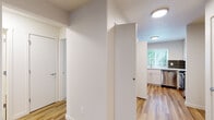 This single-floor residence offers a clean, updated interior with a cohesive design aesthetic carried throughout its spaces. Light wood-tone flooring runs through the main living areas, hallways, and kitchen, lending warmth and visual continuity across the unit.

The living room is a standout space, anchored by a corner fireplace with a clean white surround and direct access to an outdoor area through a sliding glass door, allowing natural light and outdoor views to enhance the room's open feel. The angled ceiling detail adds architectural character to the space.

The kitchen features white shaker-style cabinetry, white countertops, a stainless steel undermount sink positioned beneath a window with garden views, a dark tile backsplash that adds contrast and texture, and a stainless steel dishwasher.

Two bedrooms are finished with plush neutral carpet and each include a window fitted with blinds, offering natural light and outdoor greenery views. The layout connects to two bathrooms, each appointed with white vanities, stone-look countertops, tile accents, and wood-tone flooring. One bathroom includes a sliding glass shower enclosure, while the other provides additional hallway access alongside a closet. The overall ambiance is clean, modern, and move-in ready.