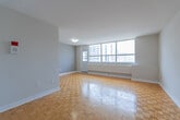 Located at 650 Parliament Street in Toronto's vibrant Cabbagetown neighbourhood, this one-bedroom, one-bathroom unit offers a practical and well-organized layout across a single floor. The living area is a standout feature, highlighted by large floor-to-ceiling windows that frame impressive views of the Toronto skyline, flooding the space with abundant natural light. Classic parquet wood flooring runs throughout the main living areas and bedroom, adding warmth and character to the bright, neutral interior.

The bedroom is a comfortable, private retreat with its own window offering city views and a baseboard heating unit, maintaining a cozy atmosphere year-round. The kitchen is efficiently laid out, featuring white cabinetry with gold-toned hardware, light stone-effect countertops, white tile flooring, and full-size appliances including a refrigerator and stove. An arched pass-through connects the kitchen seamlessly to the rest of the unit.

The bathroom is finished with crisp white subway tile surrounding a full soaking tub with an overhead shower, conveying a clean and timeless aesthetic. A hallway provides a logical flow between all rooms. Clean white walls and consistent finishes throughout give the space a cohesive, move-in-ready feel.