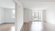 This 520-square-foot, one-bedroom, one-bathroom apartment at 1300 Fairmount Ave delivers a modern living experience through clean lines, contemporary finishes, and an efficient single-floor layout. The open-concept kitchen and living area serves as the heart of the unit, featuring a bold navy blue island with a quartz countertop, an undermount sink, and pendant lighting. The kitchen is equipped with stainless steel appliances—including a refrigerator, range, and over-the-range microwave—complemented by white upper cabinetry, navy lower cabinets, and a hexagonal tile backsplash. Wood-look flooring flows throughout the entire unit, adding warmth to the bright, white-walled interior. Large floor-to-ceiling and oversized windows in the living area and bedroom flood the space with natural light and offer views of the surrounding neighborhood. The 130-square-foot bedroom includes a double-door closet for ample storage. The bathroom is elegantly appointed with large-format hexagonal wall tiles, a soaking tub with a glass sliding door, a floating wood-toned vanity with a white countertop, and a framed mirror—creating a clean, spa-inspired aesthetic throughout.