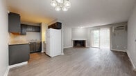 Located at 3759 Westmont Dr in Cincinnati, Ohio, this one-bedroom, one-bathroom residence offers a practical and comfortable single-floor layout. The open living area is a standout feature, showcasing light gray hardwood-style flooring that runs throughout the space, neutral gray walls, and a charming brick fireplace that serves as a focal point. A sliding glass door floods the living room with natural light and provides direct access to a private balcony overlooking lush greenery. An accent wall of painted brick adds architectural character near the entryway. The kitchen is efficiently designed with dark cabinetry, ample counter space, and standard appliances, flowing seamlessly into the living and dining area. A chandelier-style light fixture anchors the dining space. The spacious bedroom offers a generous footprint with a large window framing tree-lined views, a baseboard heating unit, and direct access to both a dedicated closet and the full bathroom. The bathroom is clean and functional with a full tub-shower combo. Additional features include a wall-mounted air conditioning unit and baseboard heating in the living area, ensuring year-round comfort throughout this well-appointed Cincinnati residence.