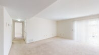 This single-floor residence offers a clean, neutral palette throughout, creating a bright and versatile living environment. The expansive main living area is finished with plush wall-to-wall carpeting and features a striking angled ceiling detail that adds architectural interest. A large sliding glass door fitted with vertical blinds allows abundant natural light to pour in, opening the space to the outdoors. The living area flows seamlessly into a dining and secondary living space, where rich hardwood-style flooring takes over, grounded by a ceiling fan overhead.

The galley-style kitchen is efficiently laid out with ample cream cabinetry, granite-style countertops, a double-basin sink, and white appliances including an electric range and refrigerator. Warm wood accents on select cabinet panels add a touch of contrast and character.

The bedrooms are carpeted and generously sized, each bathed in natural light through window blinds that filter soft, even illumination. The full bathroom is thoughtfully appointed with sage-green square tile surrounding the tub and shower, rich hardwood-style flooring, a granite-top vanity, and clean white fixtures, offering a cohesive and practical design. Overall, the space presents a well-organized, move-in-ready layout with a light, airy ambiance throughout.